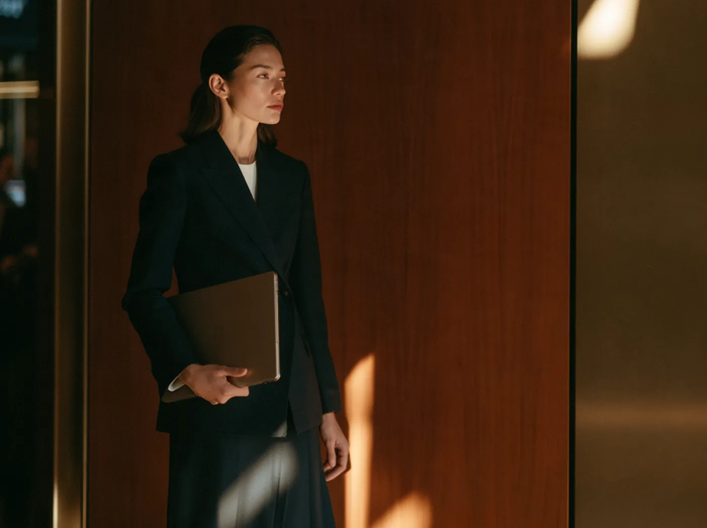 Woman holding a laptop in a wood-paneled office
